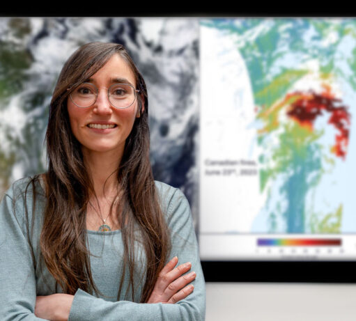Een vrouwelijke onderzoekster staat voor een groot beeldscherm waarop op een kaart in kleuren aangegeven concentraties stoffen in de atmosfeer te zien zijn.